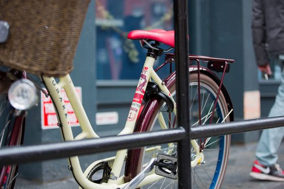 Gul cykel, med röd sadel, röda stänkskärmar, ljus cykelkorg.